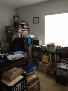 View behind desk of stacked files and clutter.